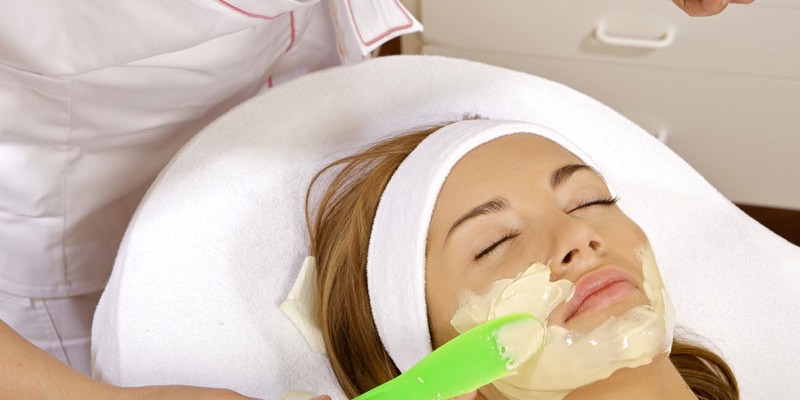 Young woman getting beauty skin mask treatment on her face with